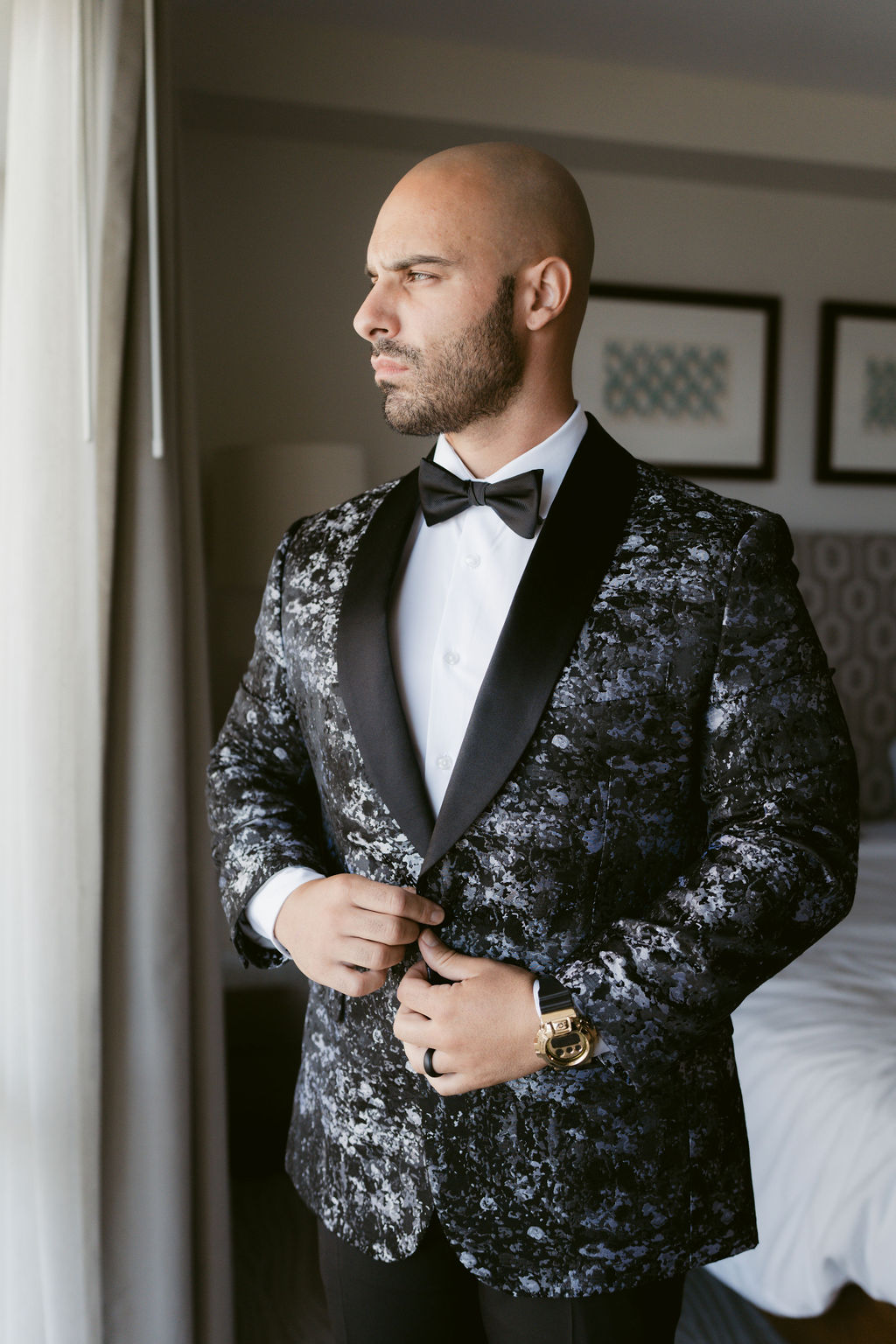 A man in a patterned tuxedo looks out a window for a micro wedding in oahu