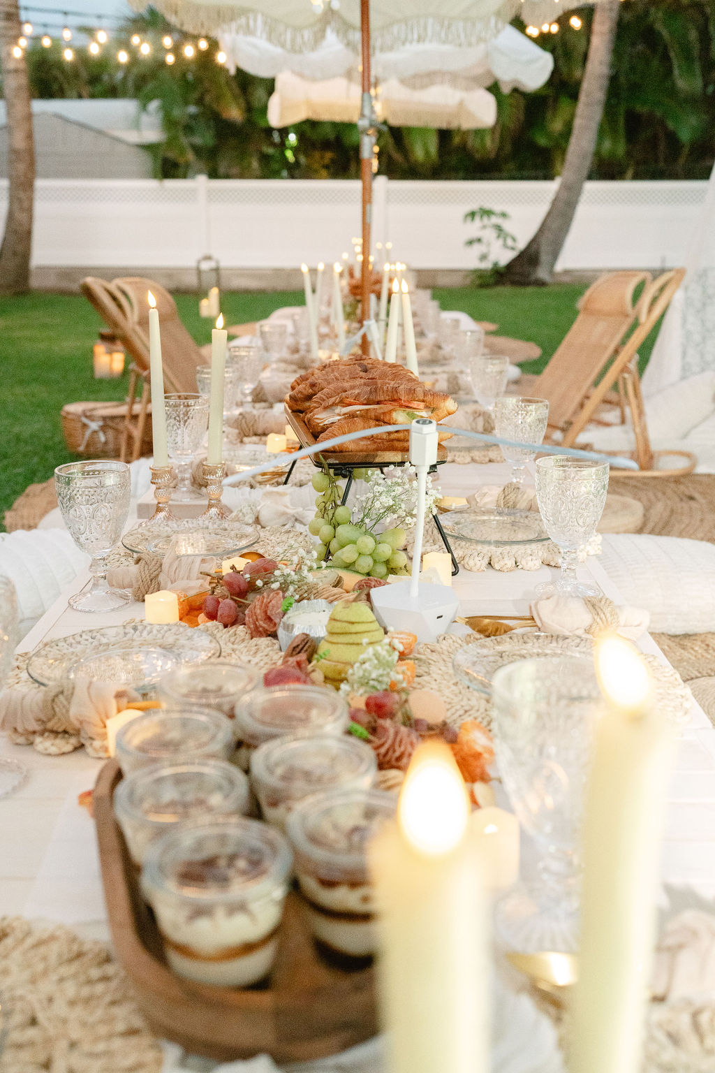 Outdoor dining table set with food, candles, and string lights for a micro wedding in oahu