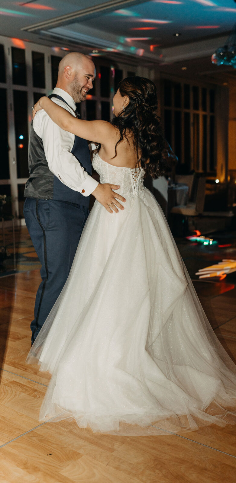 People dancing energetically at a wedding reception with a woman in a white dress leading the dance.