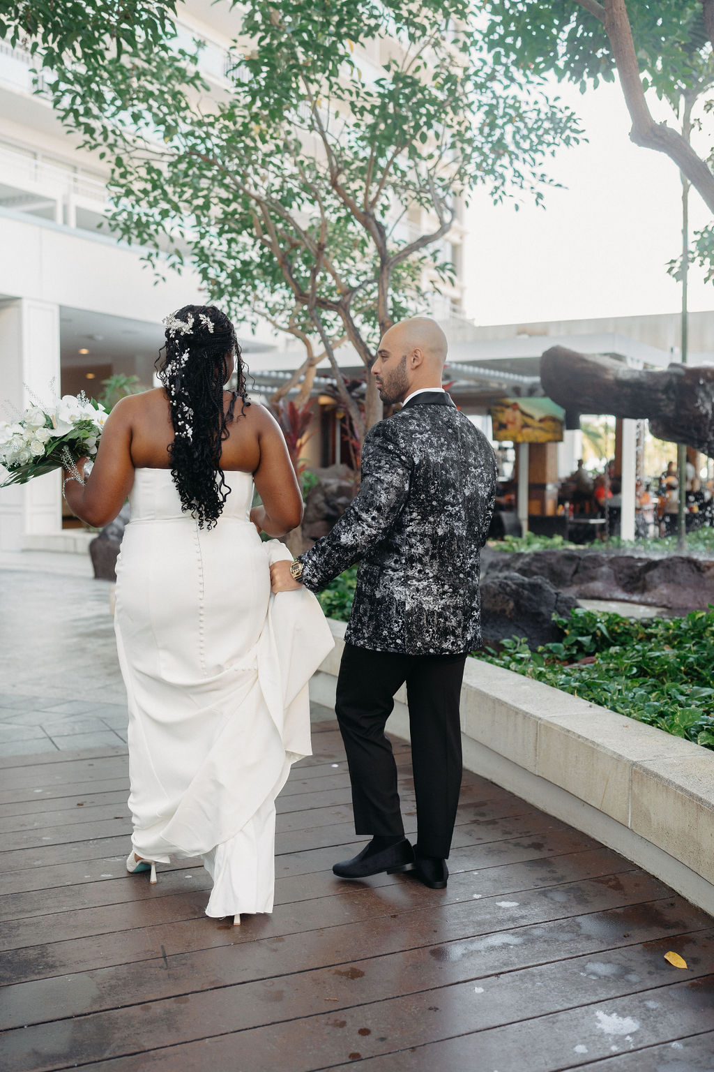 couple takes portraits outside of hotel for their destination wedding in Oahu, Hawaii