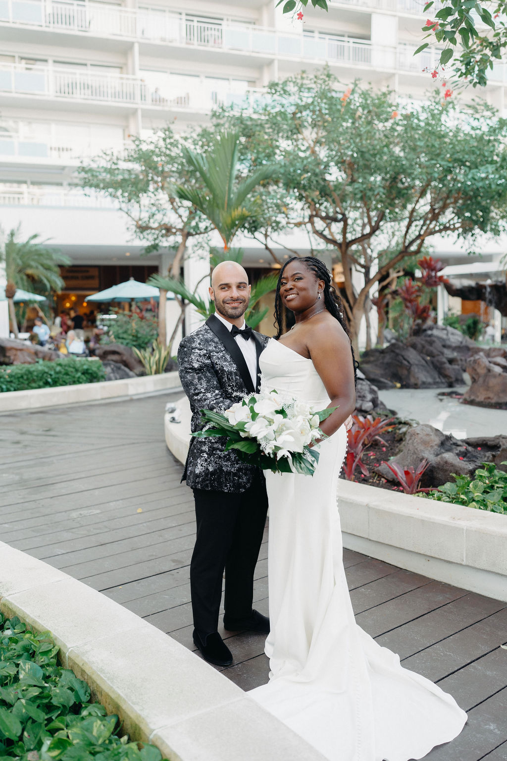 couple takes portraits outside of hotel for their destination wedding in Oahu, Hawaii