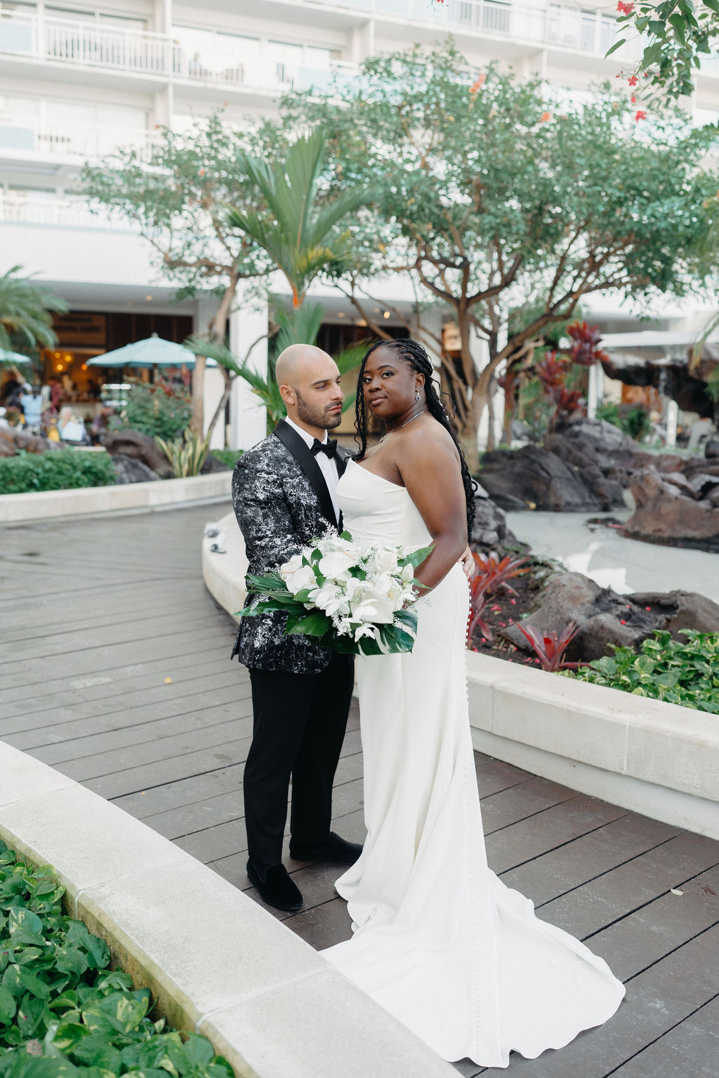 couple takes portraits outside of hotel for their destination wedding in Oahu, Hawaii