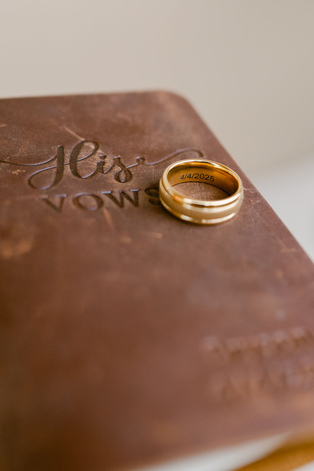 A gold ring and a silver ring with a blue stone rest on handwritten journal pages with leafy green plant in the corner.