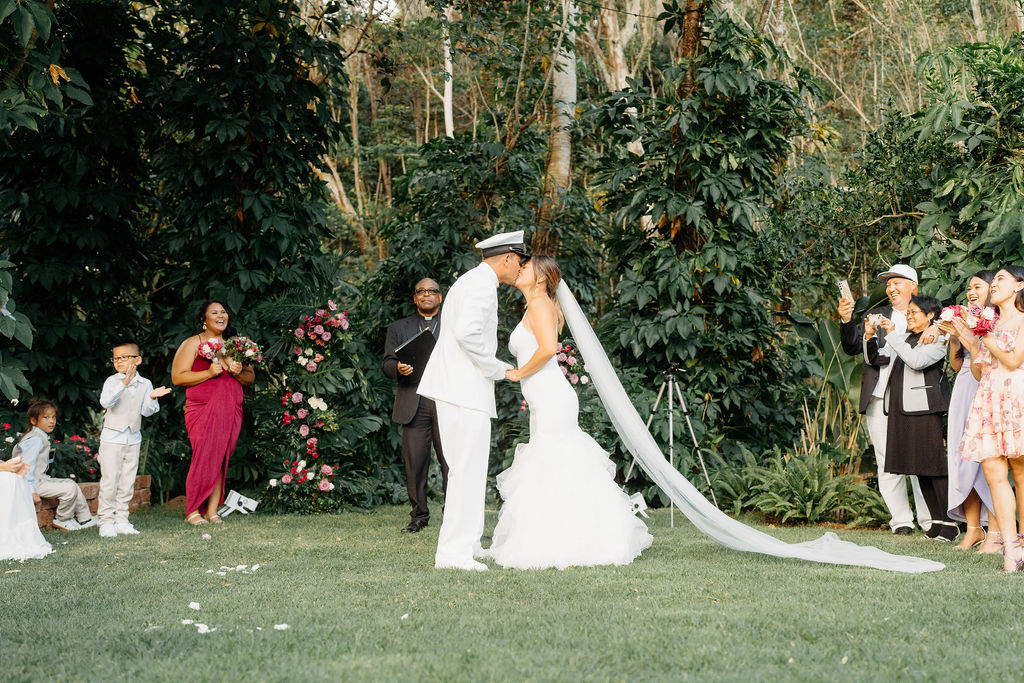 outdoor Backyard wedding ceremony in Oahu, couple stands at the end of the aisle while they share their first kiss