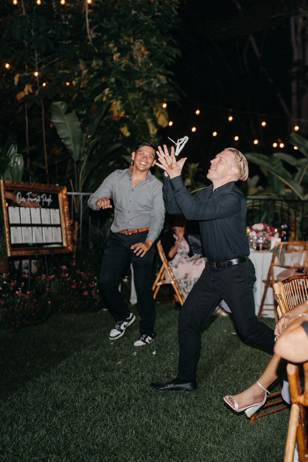 A group of people dressed in formal attire dance together at an outdoor backyard wedding in Oahu