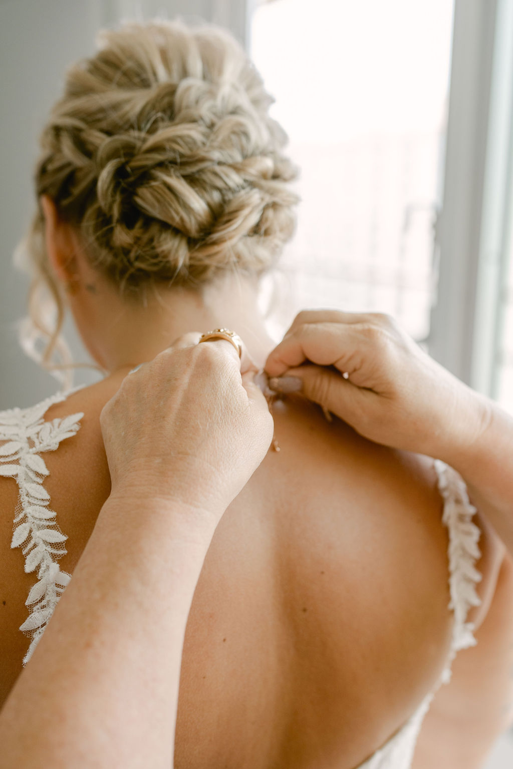 A bride in a white wedding dress and veil looks at herself in a mirror, with her hand resting on the frame for a wedding at Queen Kapiolani Hotel 