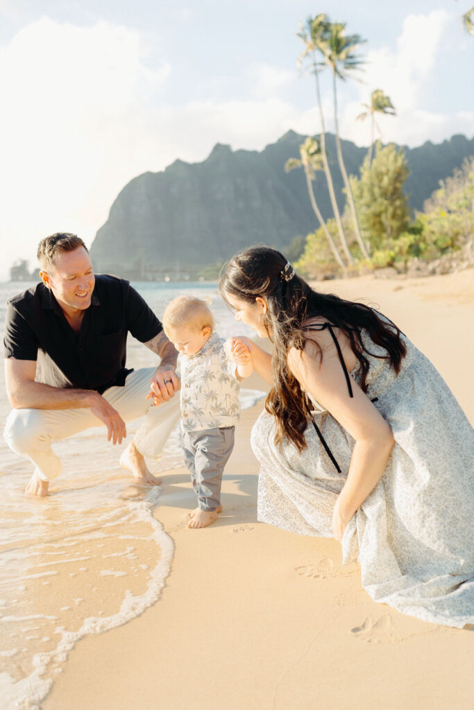 family takes Hawaii family photos on Kaaawa beach at sunset with a toddler