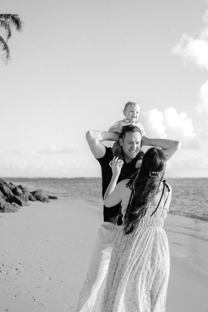 family takes Hawaii family photos on Kaaawa beach at sunset with a toddler