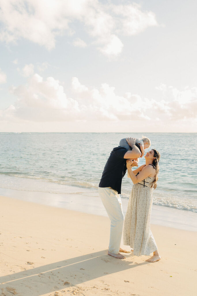 family takes Hawaii family photos on Kaaawa beach at sunset with a toddler