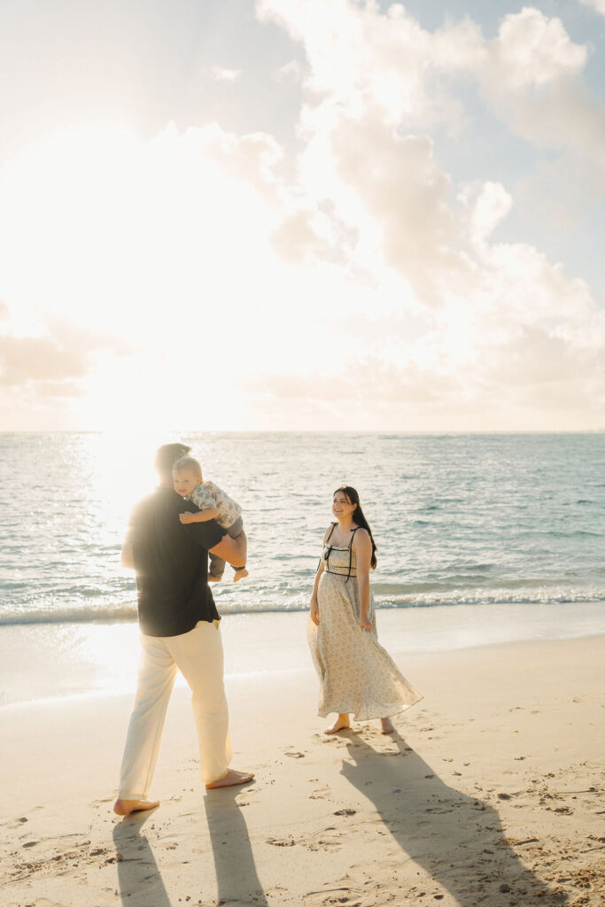 family takes Hawaii family photos on Kaaawa beach at sunset with a toddler