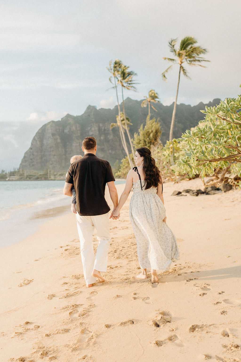 amily takes Hawaii family photos on Kaaawa beach at sunset with a toddler