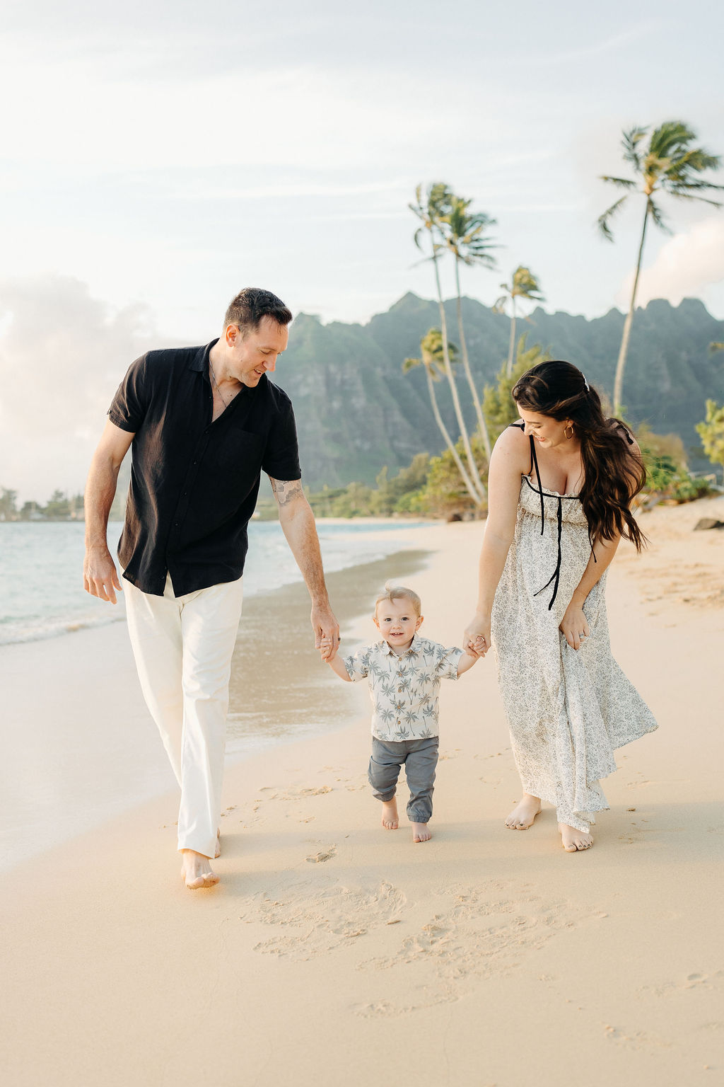 amily takes Hawaii family photos on Kaaawa beach at sunset with a toddler